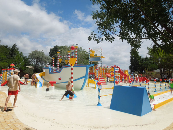Kinderen spelen bij een groot piratenschip in de ondiepe waterspeeltuin op Camping Le Sérignan Plage in Frankrijk.