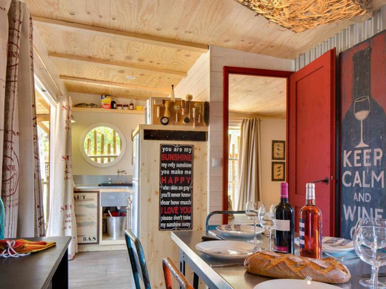 Sfeervol ingericht interieur van een 'Robinson' stijl stacaravan met houten details en een keukentje op Camping Le Sérignan Plage.