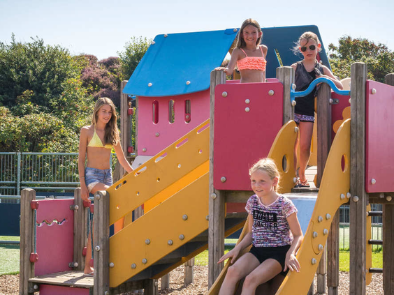 Kinderen spelen en klimmen op een kleurrijk speeltoestel in de buitenspeeltuin van Camping Loodsmansduin.