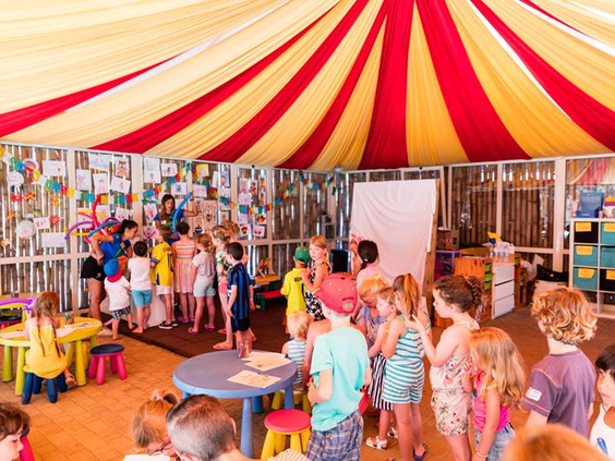 Kinderen doen mee aan creatieve activiteiten onder rood-gele circustent bij Camping Park Albatros