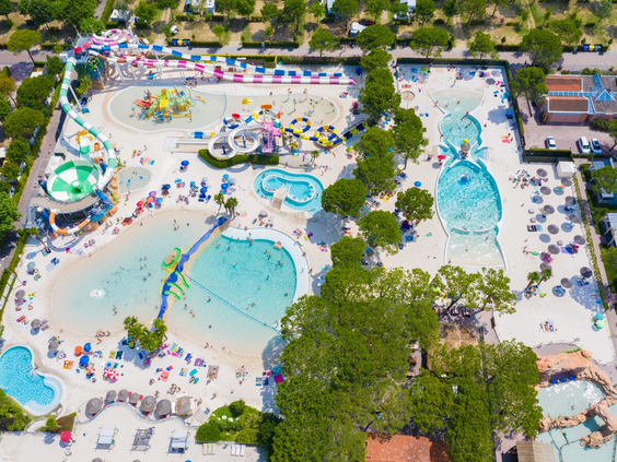 Luchtfoto van het immense Aquapark Laguna op Camping Union Lido, met diverse lagune zwembaden, witte zandstranden en veel vakantiegangers.