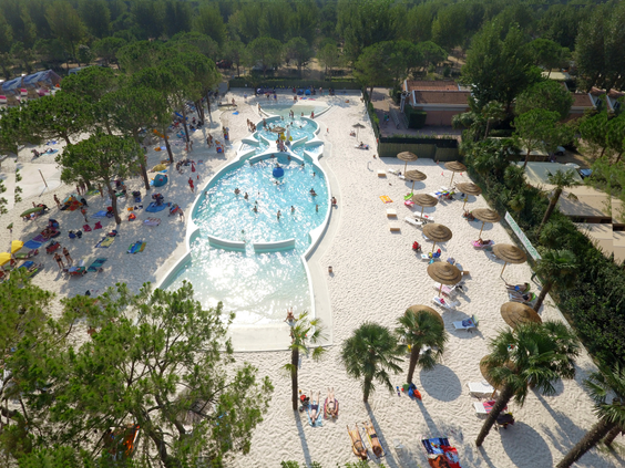 Luchtfoto van Aquapark Laguna op Camping Union Lido, een groot zwembadcomplex met zandstranden, palmbomen en veel zwemmende gasten.