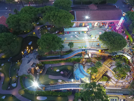 Sfeervol verlicht attractiepark op Camping Union Lido in de avond, gezien van boven, met een midgetgolfbaan en andere attracties.