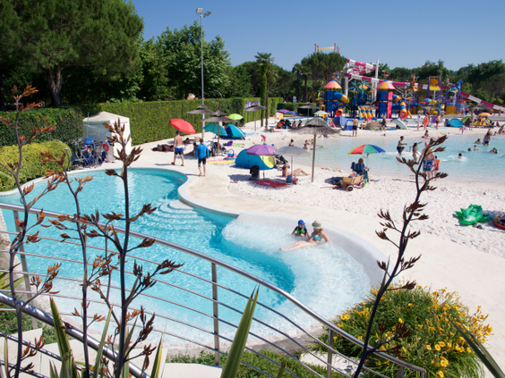 Gedeelte van Aquapark Laguna op Camping Union Lido, met een zwembad dat een zacht aflopende rand van wit zand heeft waar kinderen kunnen spelen.
