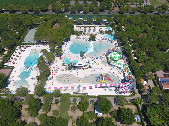 Luchtfoto van het complete Aquapark Marino op Camping Union Lido, omringd door bomen, met glijbanen, een trechterglijbaan en diverse zwembaden.