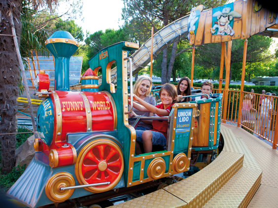 Kinderen en ouders maken een vrolijk ritje in de achtbaan in de vorm van een trein in het attractiepark van Camping Union Lido.