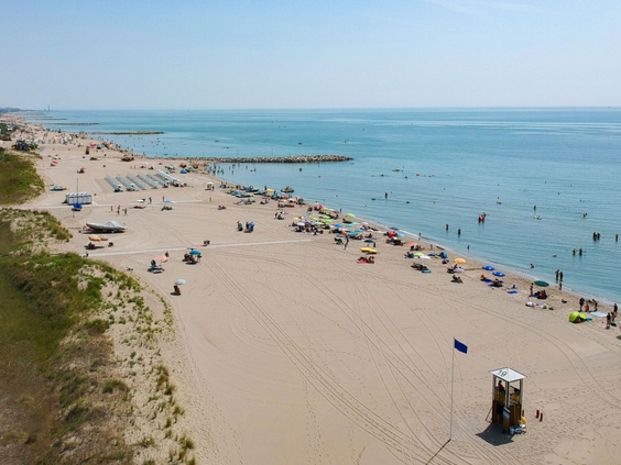 Overzicht van het brede zandstrand aan de Adriatische kust bij Camping Union Lido, waar vakantiegangers genieten van de zon en de zee.