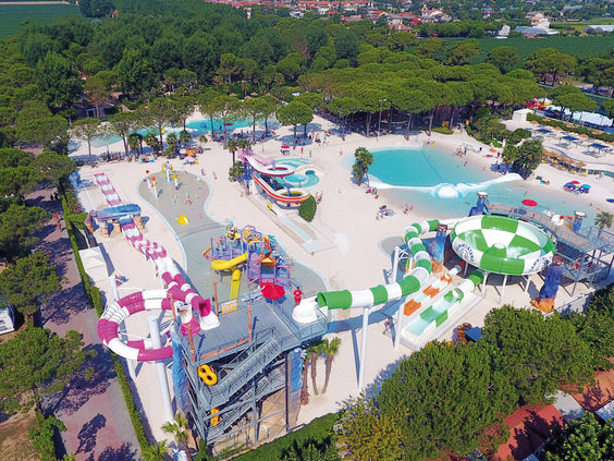 Luchtfoto van het spectaculaire Aquapark Marino op Camping Union Lido, vol met kleurrijke waterglijbanen, een trechterglijbaan en diverse zwembaden.