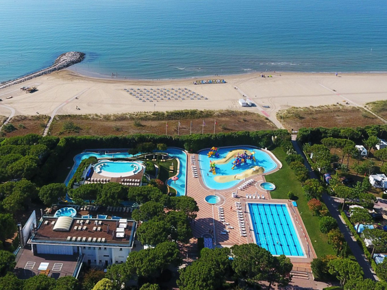 Luchtfoto van Camping Union Lido met een van de zwembadcomplexen direct gelegen aan het brede zandstrand en de Adriatische Zee.