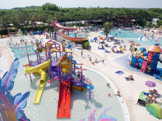 Overzicht van de kleurrijke waterspeeltuin in een van de aquaparken op Camping Union Lido, vol met glijbanen, speeltoestellen en spetterende kinderen.