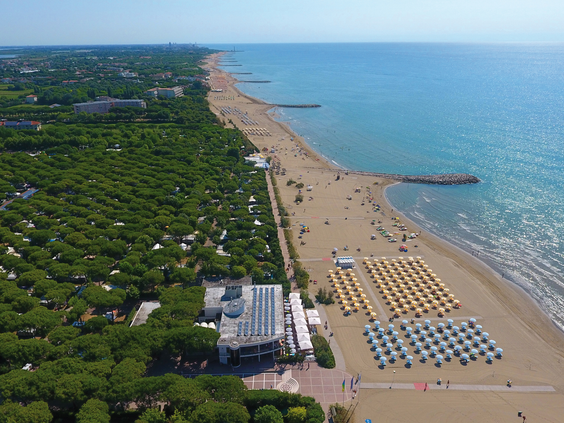 Luchtfoto van het brede en lange privé zandstrand van Camping Union Lido aan de Venetiaanse Rivièra, met rijen ligbedjes en parasols.