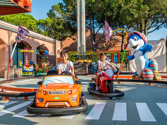 Twee jongens hebben plezier in de elektrische auto's en motoren in het attractiepark op Camping Union Lido.