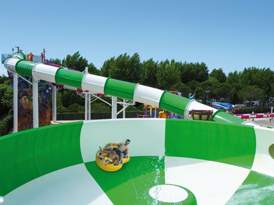 Bezoeker komt met een opblaasband uit de waterglijbaan en tolt rond in de grote trechter in Aquapark Marino op Camping Union Lido.