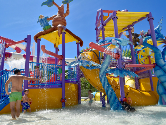 Kinderen spelen in het grote, kleurrijke waterspraypark met meerdere glijbanen en watertoestellen op Camping Union Lido.