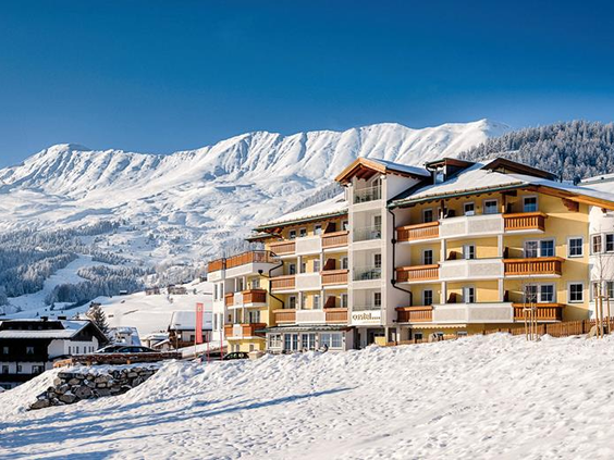 Hotel in de sneeuw met een hoge besneeuwde bergtop achter zich