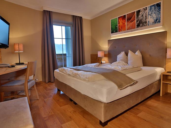 Hotelkamer met comfortabel tweepersoonsbed, nachtkastjes, moderne inrichting en zachte verlichting.