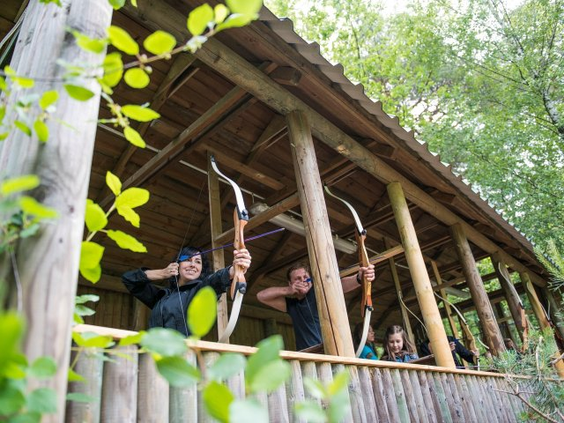 Een familie leert boogschieten met pijl en boog tijdens een workshop in de outdoor schietbaan van Center Parcs Bispinger Heide.
