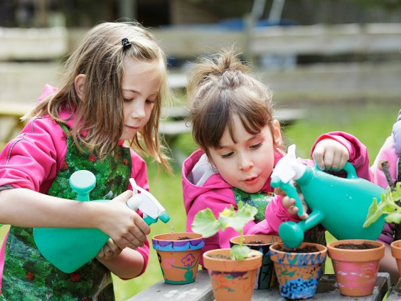 Twee meisjes geven een plantje water in een zelf versierd potje tijdens de kinderactiviteit Wannabe een Tuinier bij Center Parcs Bispinger Heide.