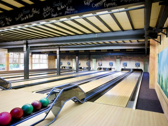 Een overzicht van de moderne bowlingbanen met kleurrijke bowlingballen op de voorgrond bij Center Parcs Bispinger Heide.
