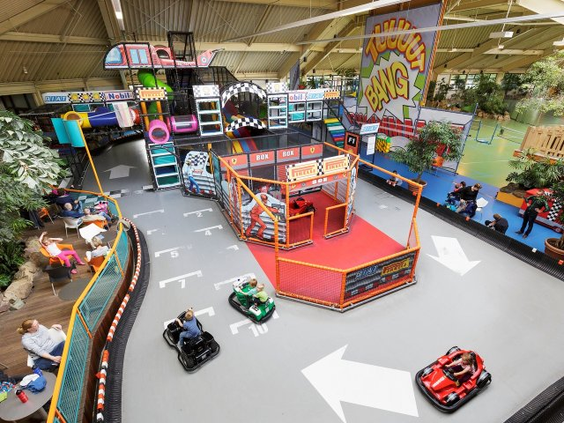 Kinderen rijden op een kartbaan met elektrische autootjes in de grote BALUBA binnenspeelwereld van Center Parcs Bispinger Heide.