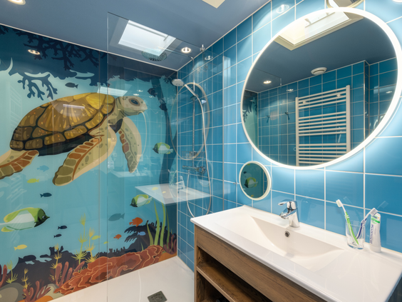 Een themabadkamer voor kinderen in een 'Dieren in het bos' cottage, met een vrolijke tegelwand die een onderwaterwereld met een grote zeeschildpad uitbeeldt.