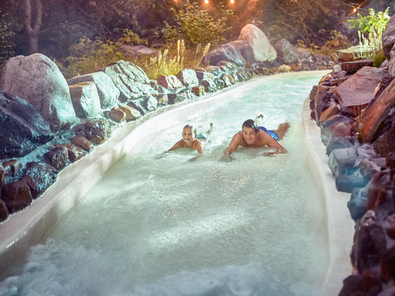 Een vader en dochter hebben plezier terwijl ze op hun buik door de wildwaterbaan van de Aqua Mundo bij Center Parcs De Kempervennen glijden.