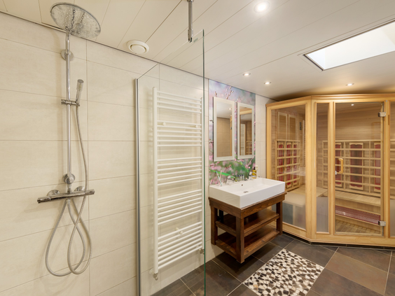 De luxe badkamer van een VIP cottage in Het Meerdal, met een ruime inloopregendouche, een wastafel en een houten tweepersoons infraroodsauna.