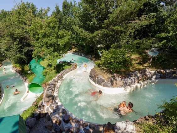 De wildwaterbaan van Aqua Mundo bij Het Meerdal die zich door een groene, bosrijke omgeving slingert, met verschillende mensen in het water.