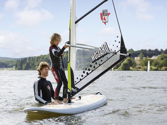 Een kind krijgt windsurfles van een instructeur op het Bostalmeer bij Center Parcs.