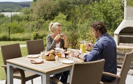 Een gezin geniet van een uitgebreid ontbijt aan de eettafel op het terras van hun cottage bij Center Parcs Park Bostalsee.