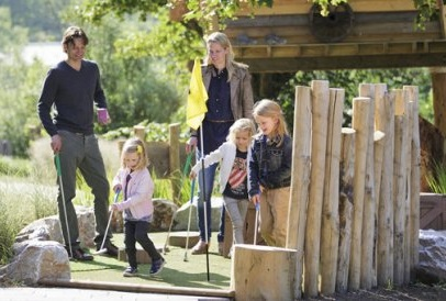 Een gezin met jonge kinderen speelt samen een potje midgetgolf op de avontuurlijke midgetgolfbaan van Center Parcs.