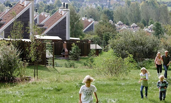 Kinderen spelen in de heuvelachtige, groene omgeving van Center Parcs Park Hochsauerland met de vakantiehuizen op de achtergrond.