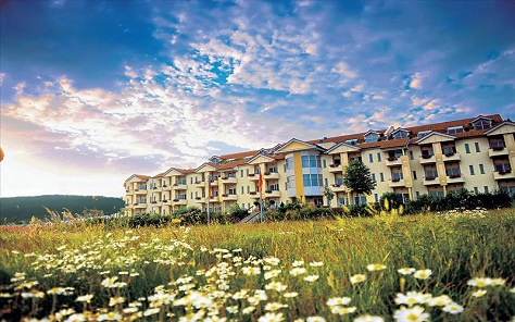 De appartementen van Center Parcs Park Hochsauerland, gelegen in een veld vol met witte en gele bloemen.