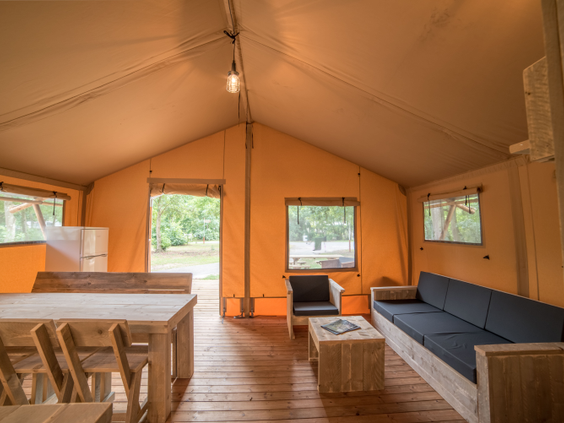 Het ruime en sfeervolle interieur van een luxe safaritent op Center Parcs Port Zélande, compleet met zithoek, eethoek en keukenblok.