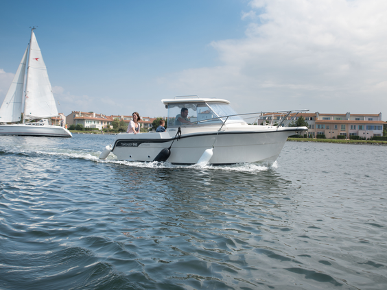 Een motorboot vaart op het Grevelingenmeer bij Center Parcs Port Zélande op een zonnige dag, met een zeilboot op de achtergrond.