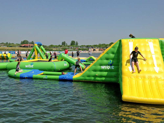 Kinderen en volwassenen klimmen en klauteren op het grote opblaasbare Aquapark op het Grevelingenmeer bij Center Parcs Port Zélande.
