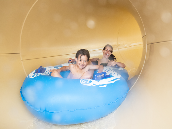 Twee personen glijden samen op een rubberband door een overdekte bochtglijbaan bij Center Parcs Port Zélande