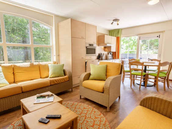 Het interieur van een cottage op Center Parcs Port Zélande met een gezellige zithoek, eethoek en een open keuken.