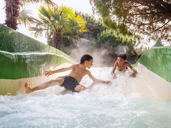 Twee jongens roetsjen met volle snelheid naar beneden in de wildwaterbaan van de Aqua Mundo op Center Parcs Port Zélande.