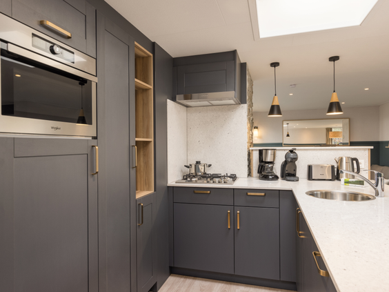 De moderne en volledig uitgeruste keuken in een vernieuwde VIP cottage van Center Parcs Erperheide, met een combi-magnetron en donkergrijze kasten.