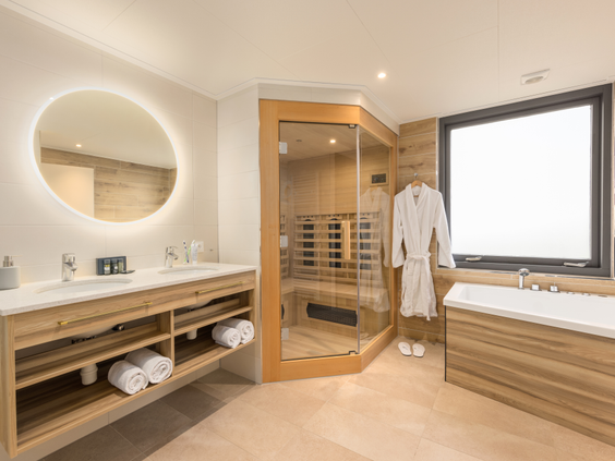 De luxe wellness-badkamer in een VIP cottage bij Center Parcs Erperheide, voorzien van een Finse sauna, een bubbelbad en een dubbele wastafel.