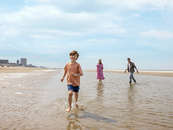 Kinderen rennen en spelen in de branding van de zee op het strand van Zandvoort, direct gelegen naast het vakantiepark van Center Parcs.