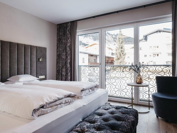Tweepersoonsbed in hotelkamer met balkon met uitzicht over de sneeuw