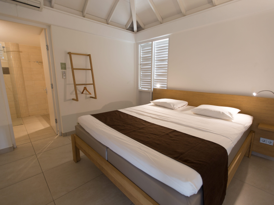 De lichte en moderne slaapkamer in een appartement van CHOGOGO Dive & Beach Resort, met een opgemaakt tweepersoonsbed.