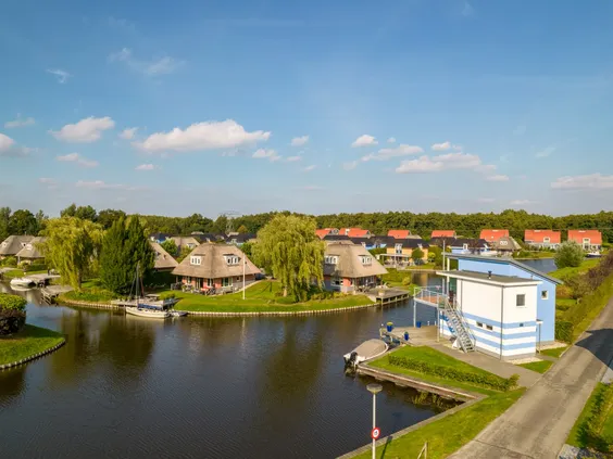 Overzicht van de diverse waterwoningen en vakantiehuizen met rieten daken die verspreid liggen aan het water op Villapark de Bloemert.