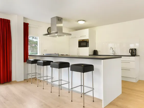 Moderne, open keuken met een groot kookeiland en barkrukken in een luxe vakantiehuis op Villapark de Bloemert.