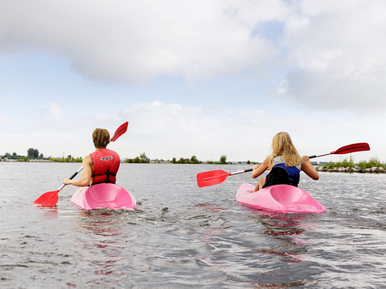 Twee personen peddelen in roze kajaks op het open water van het Eemmeer, direct gelegen aan Center Parcs De Eemhof.