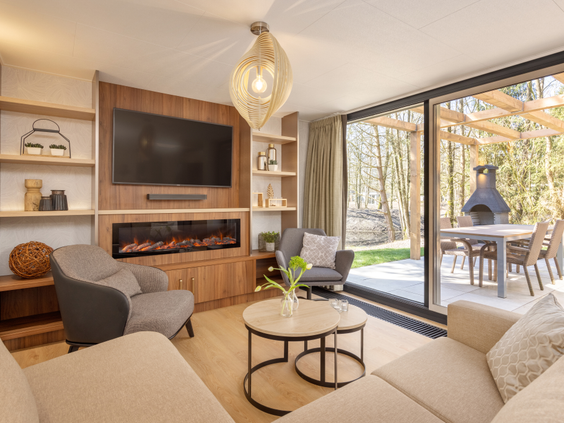 De luxe en modern ingerichte woonkamer van een Exclusive cottage bij De Eemhof, met een sfeerhaard, grote tv en uitzicht op het privéterras.