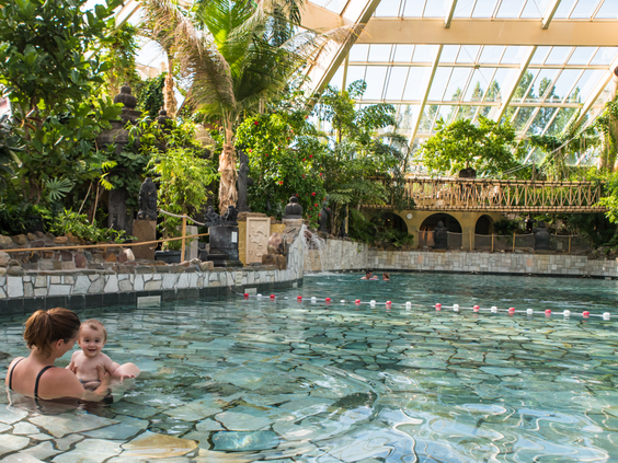 Een moeder en haar baby genieten van het warme water in een van de baden van de tropische Aqua Mundo bij Center Parcs De Eemhof.