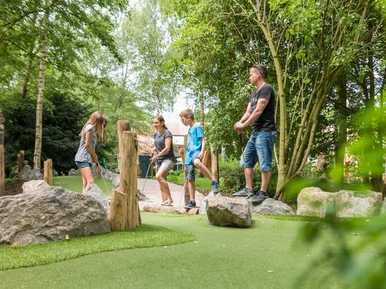 Een gezin speelt midgetgolf op de avontuurlijke en natuurlijke adventure golfbaan in de buitenlucht bij Center Parcs De Eemhof.